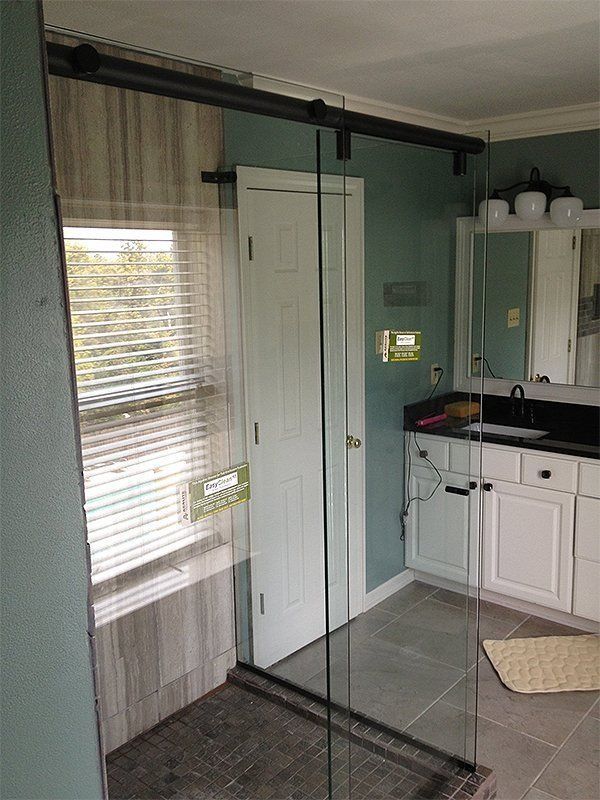 Bathroom with glass shower doors, white vanity, and teal walls next to a window with blinds.