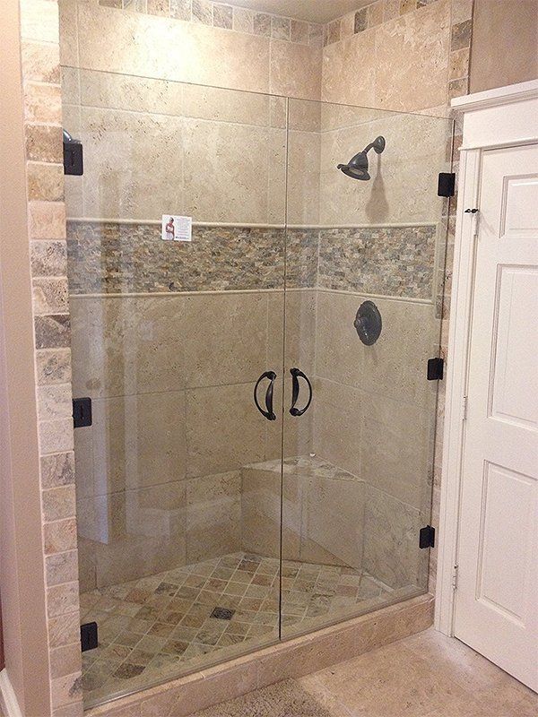 Walk-in shower with beige tile, glass door, and chrome fixtures in a bathroom