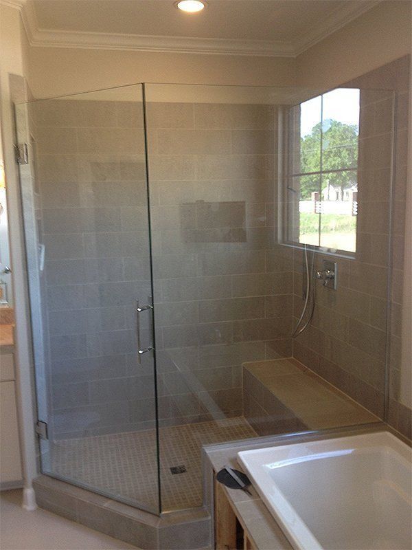 Glass-enclosed walk-in shower beside a bathtub in a bright tiled bathroom