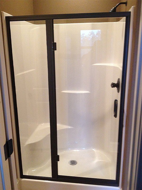 Frosted glass shower enclosure with black frame and door handle in a beige bathroom