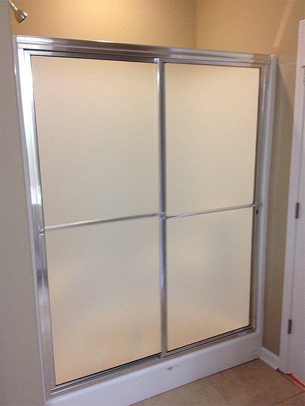 Sliding glass shower door with frosted panels and aluminum frame