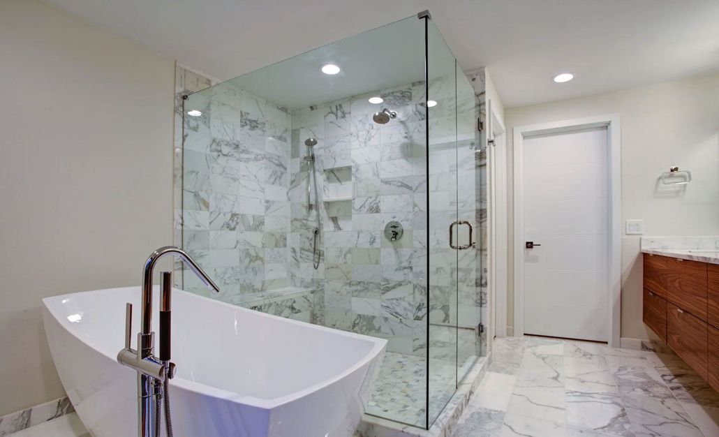 Modern bathroom with freestanding tub, glass shower, marble floors, and white door.