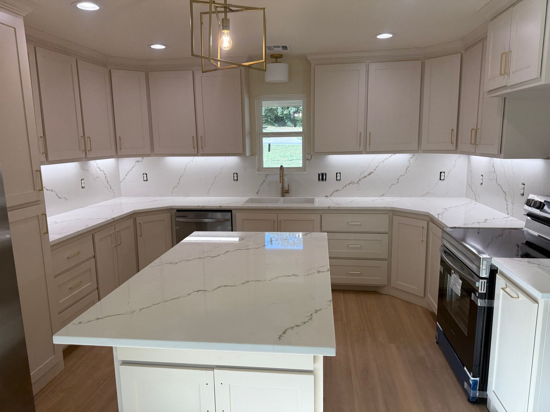 Bright white kitchen with beige cabinets, island, and stainless steel appliances