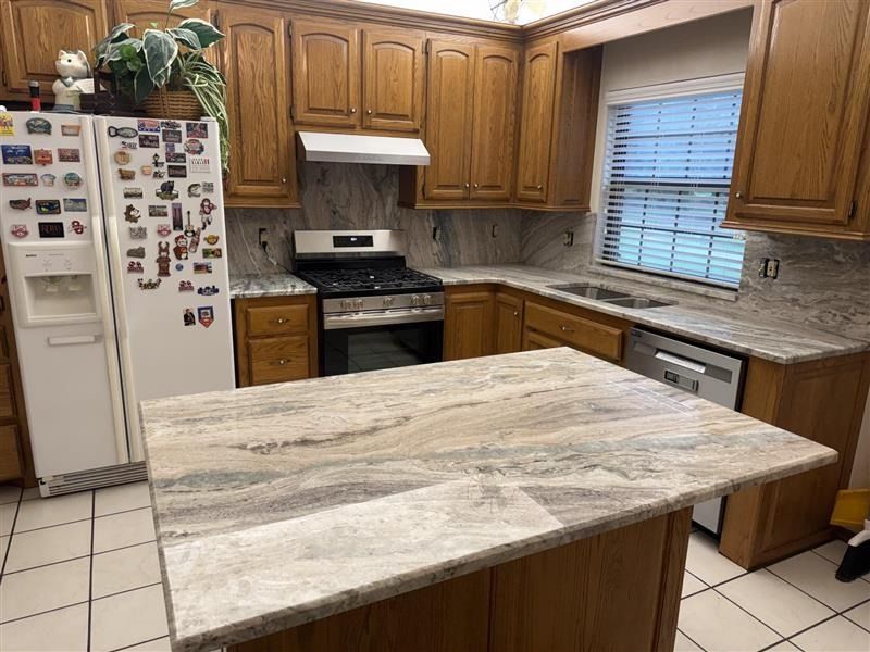 Wooden kitchen with white appliances, granite island, and tiled floor