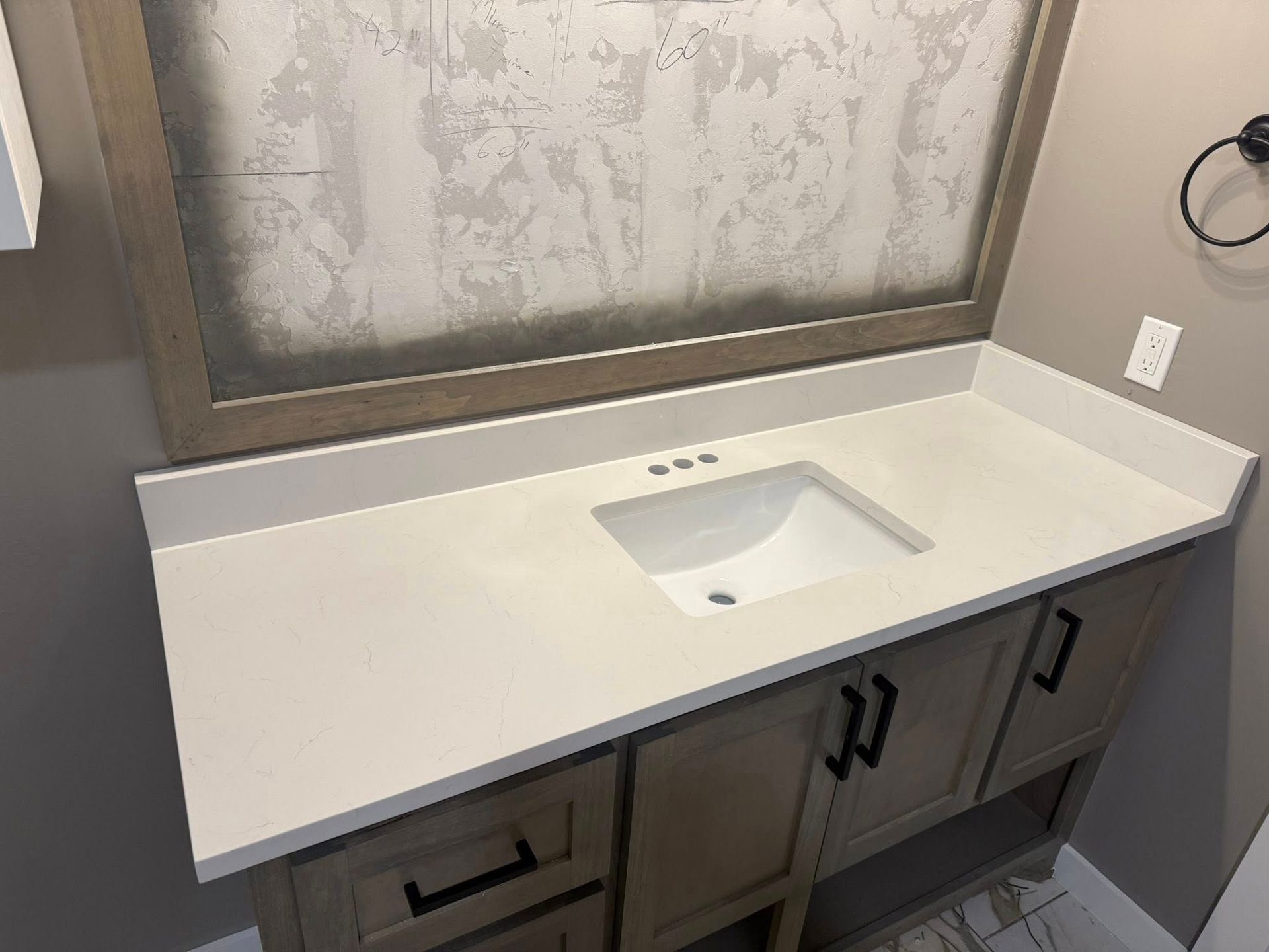 White bathroom vanity with built-in sink, gray cabinets, and a large mirror above.