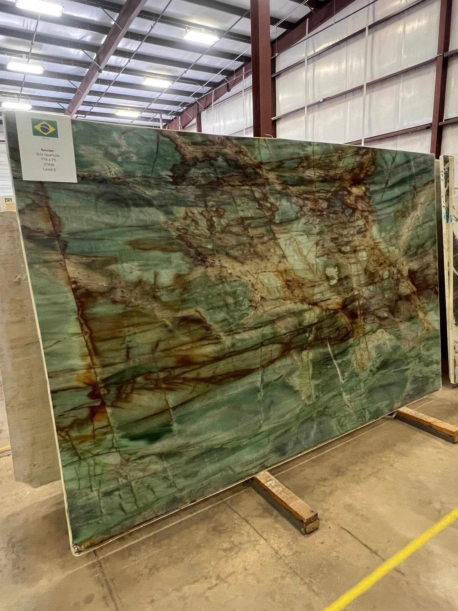 Large green veined stone slab displayed upright in an industrial warehouse.