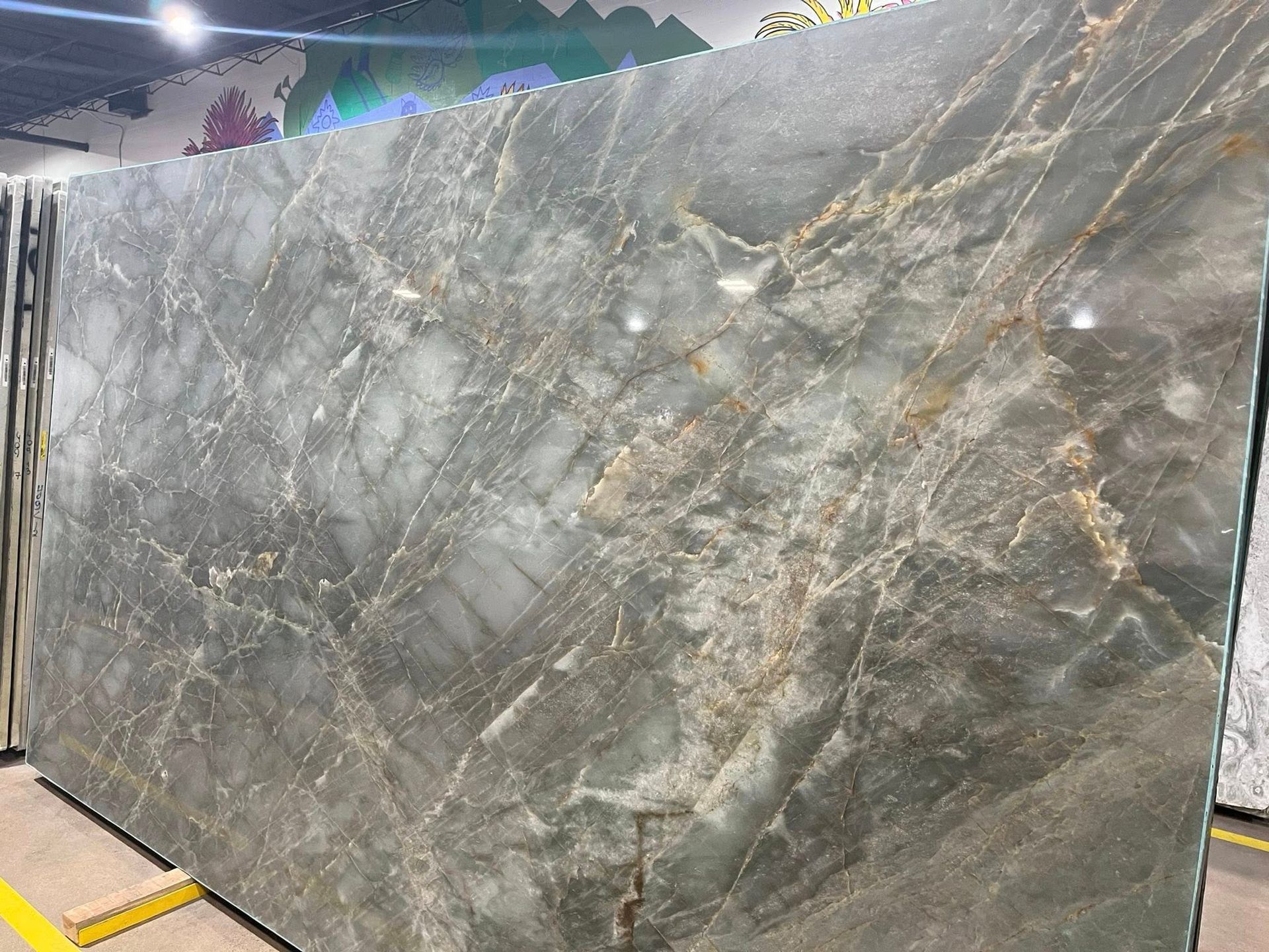 Large gray marble slab with white and gold veining leaning upright outdoors