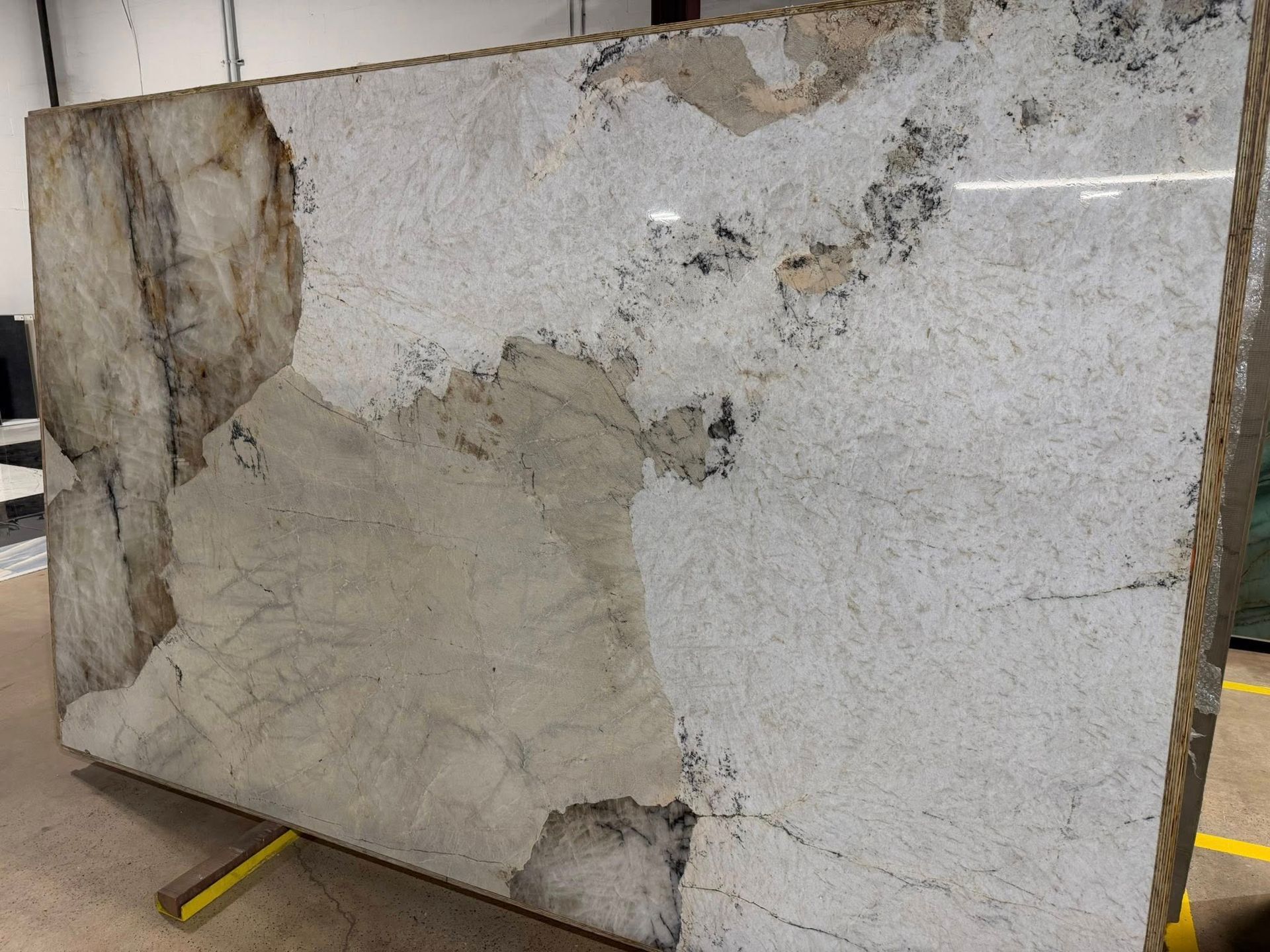 Large cracked stone slab with patches of cement repair, leaning indoors on a stand