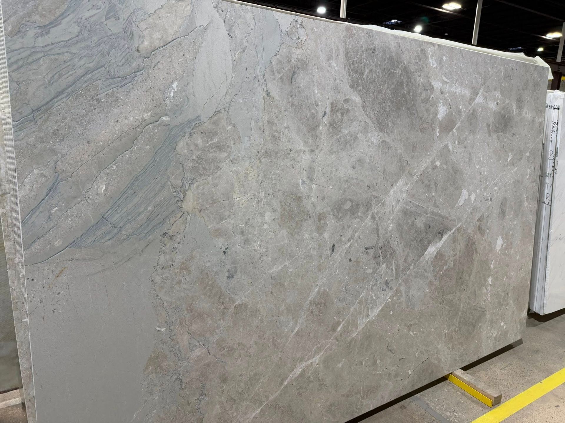 Large gray marble slab displayed upright in a warehouse or stone showroom