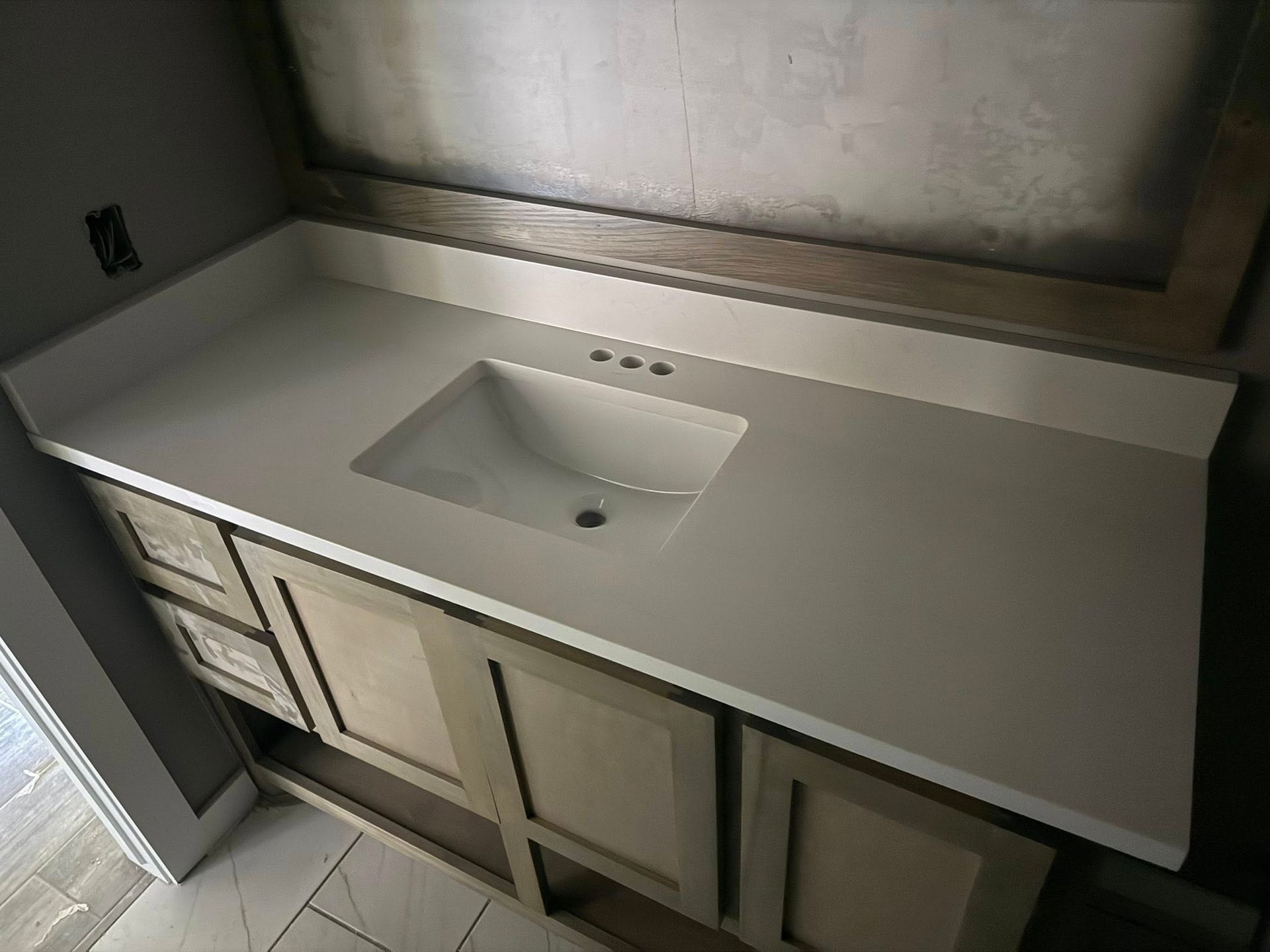 Bathroom vanity with white countertop and built-in sink beneath a mirror, seen from above.