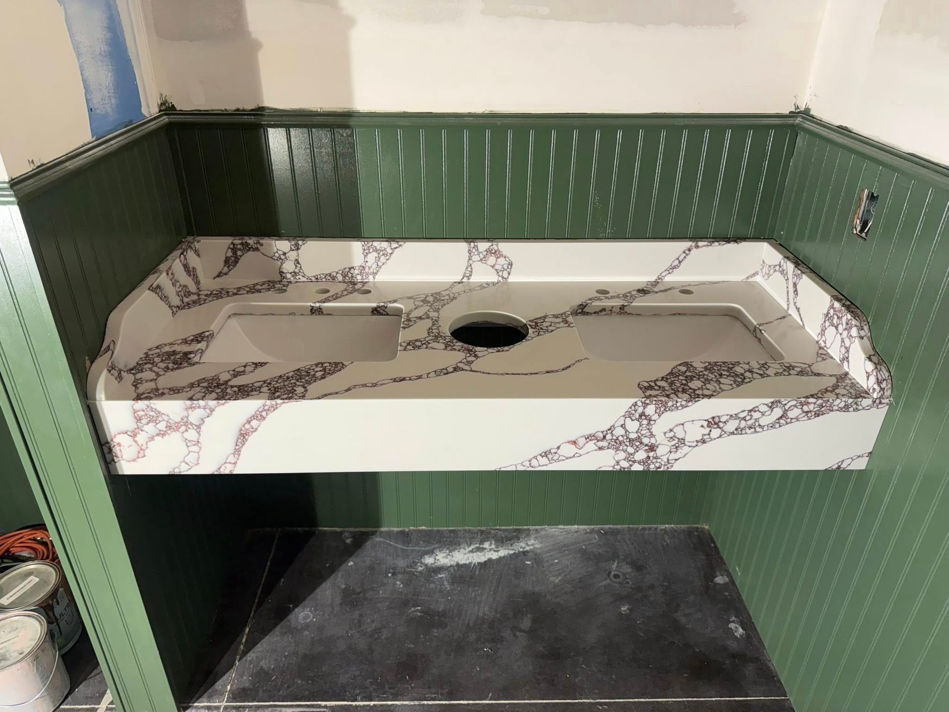 Green bathroom vanity with a patterned sink countertop and central basin hole under construction