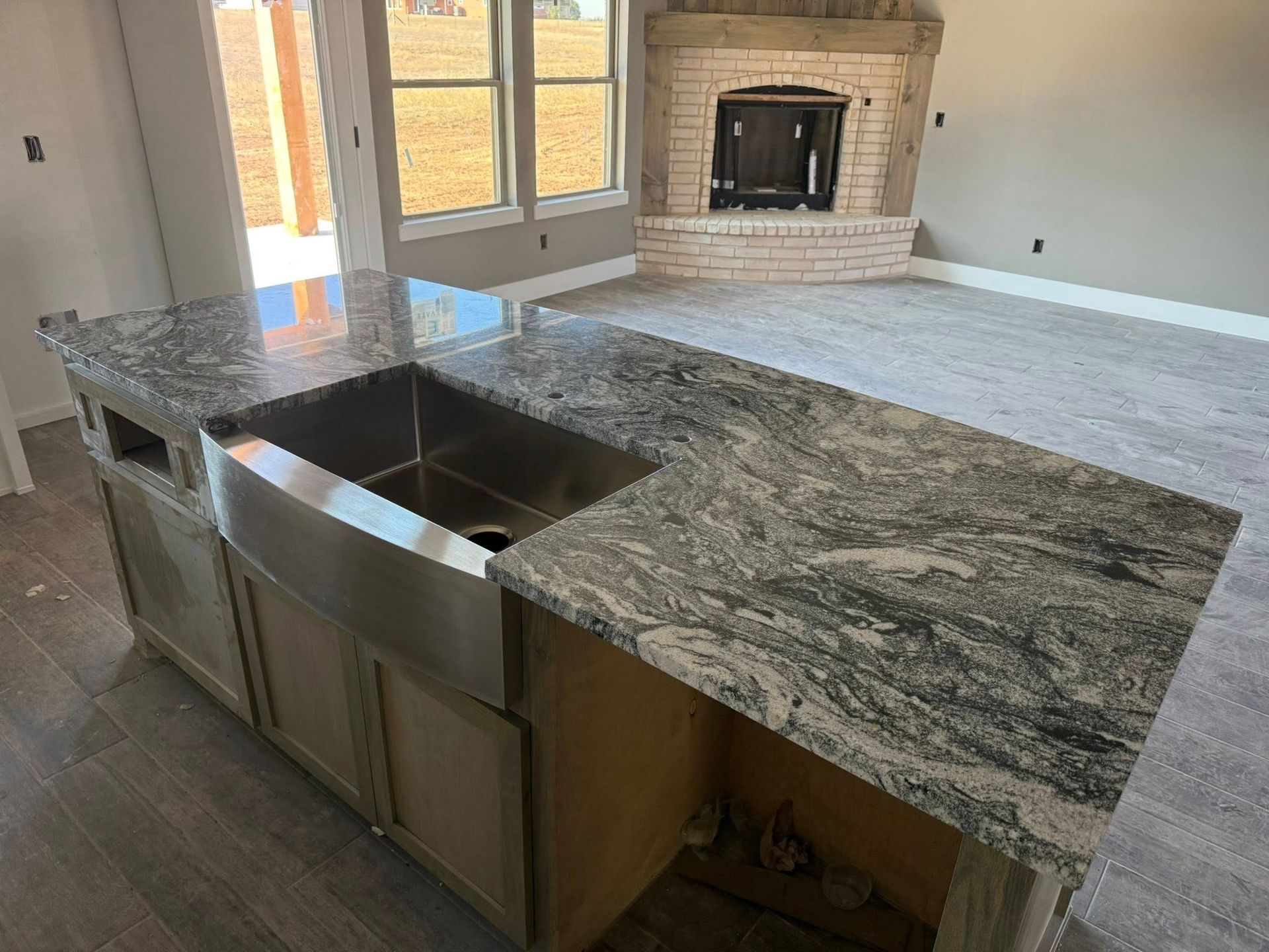 Kitchen island with stainless steel sink and granite countertop in an open living room.