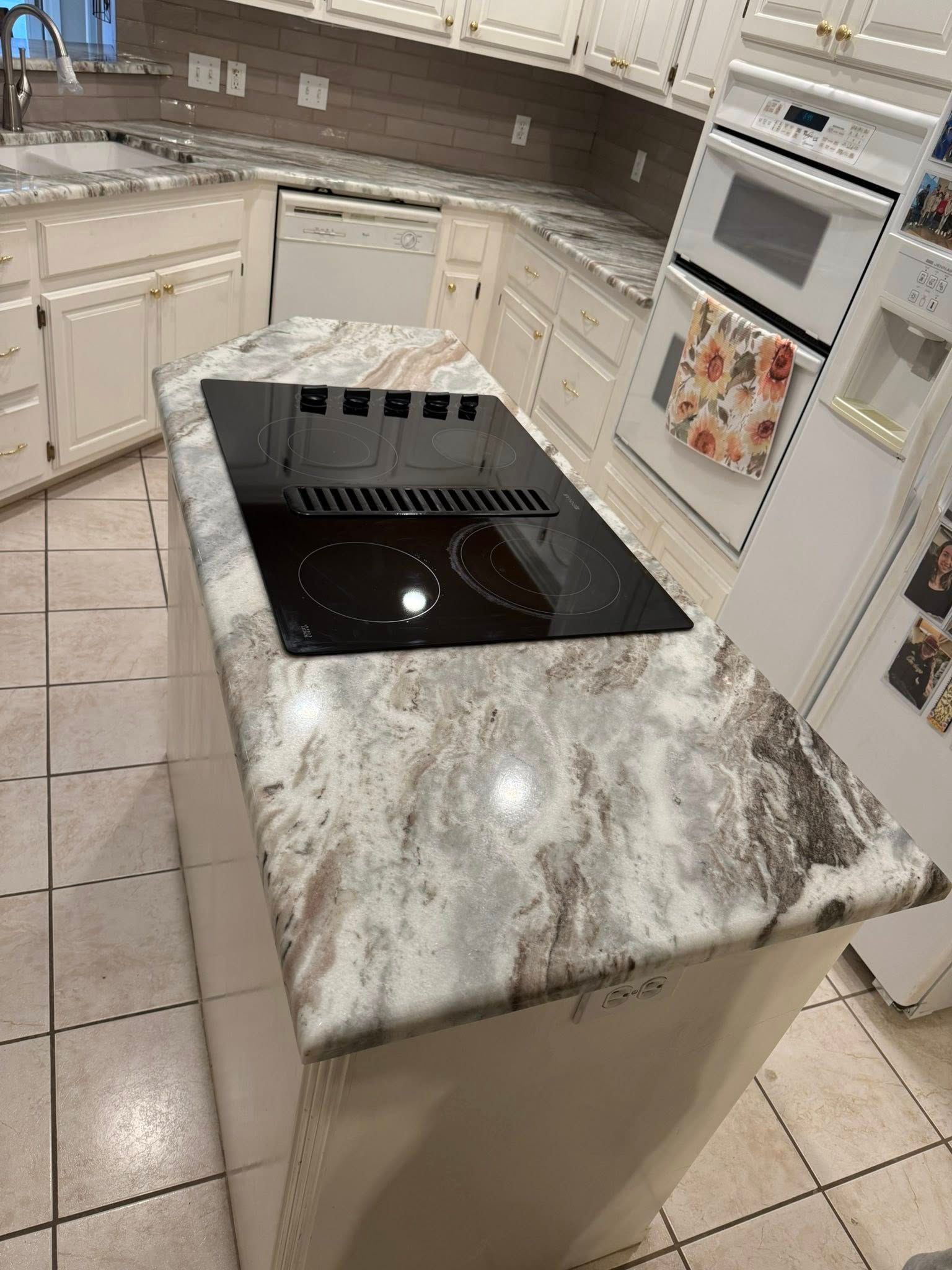 Modern white kitchen with granite island and black cooktop, viewed from above
