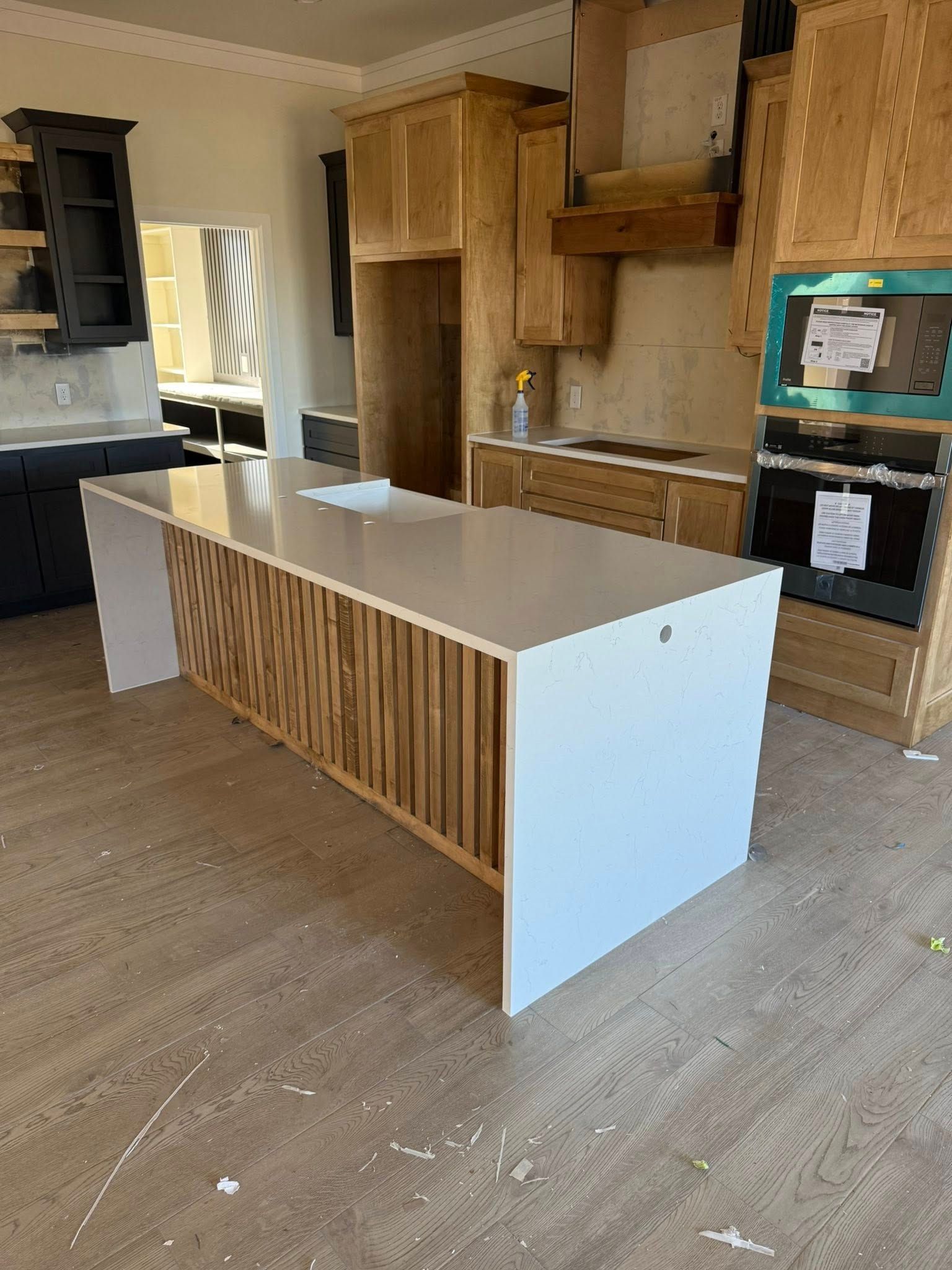 Modern kitchen with unfinished wood cabinets, white island, and beige flooring