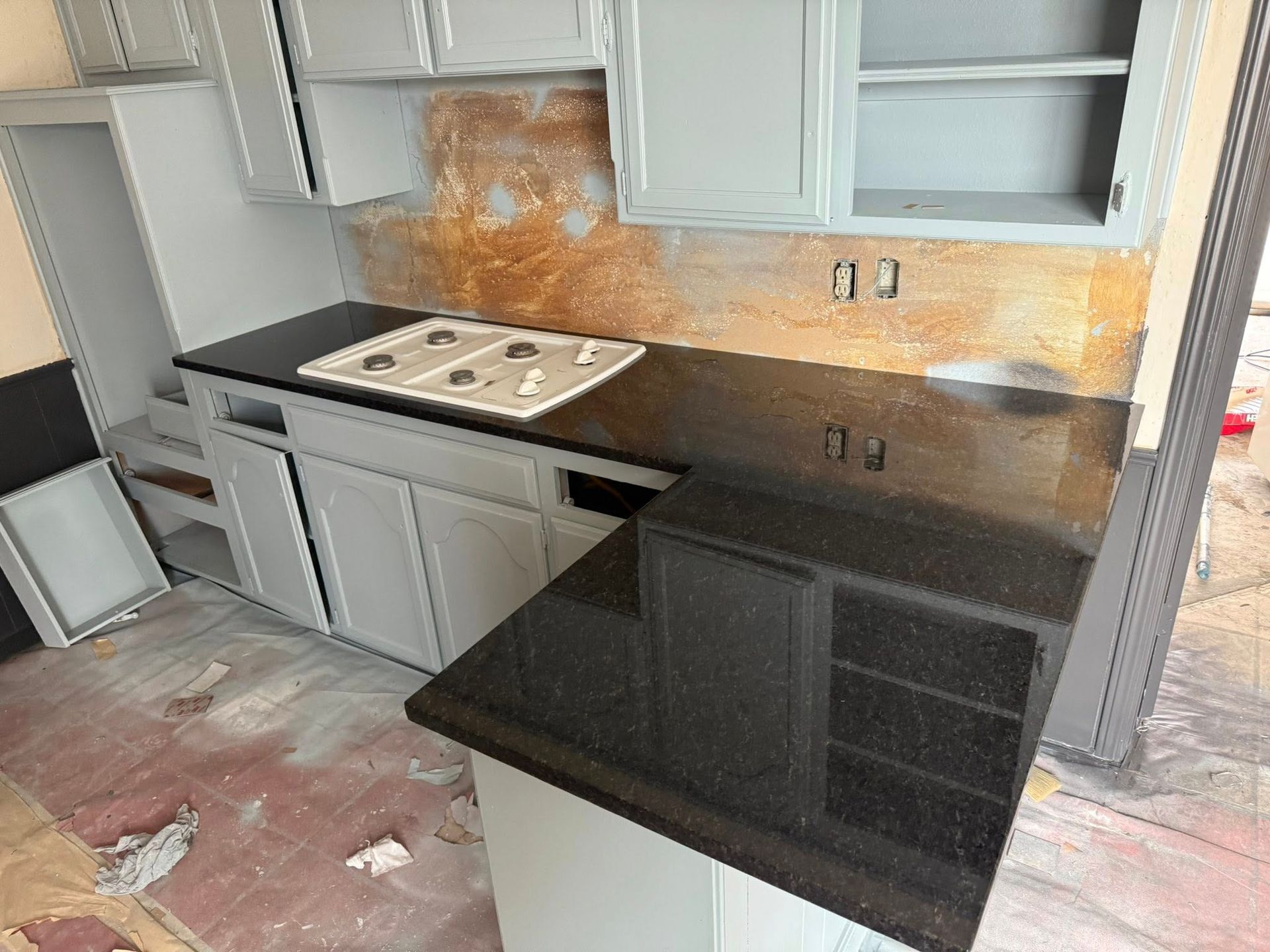 Kitchen with gray cabinets, black countertops, and an unfinished backsplash renovation area
