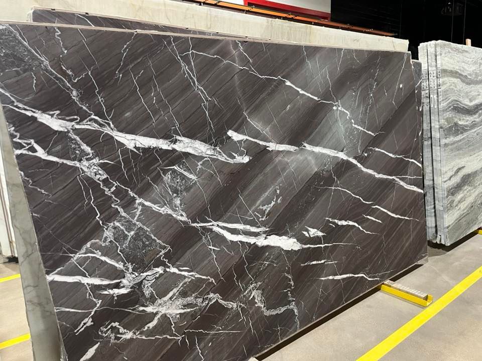 Dark brown marble slab with white veining displayed in a showroom among other stone slabs