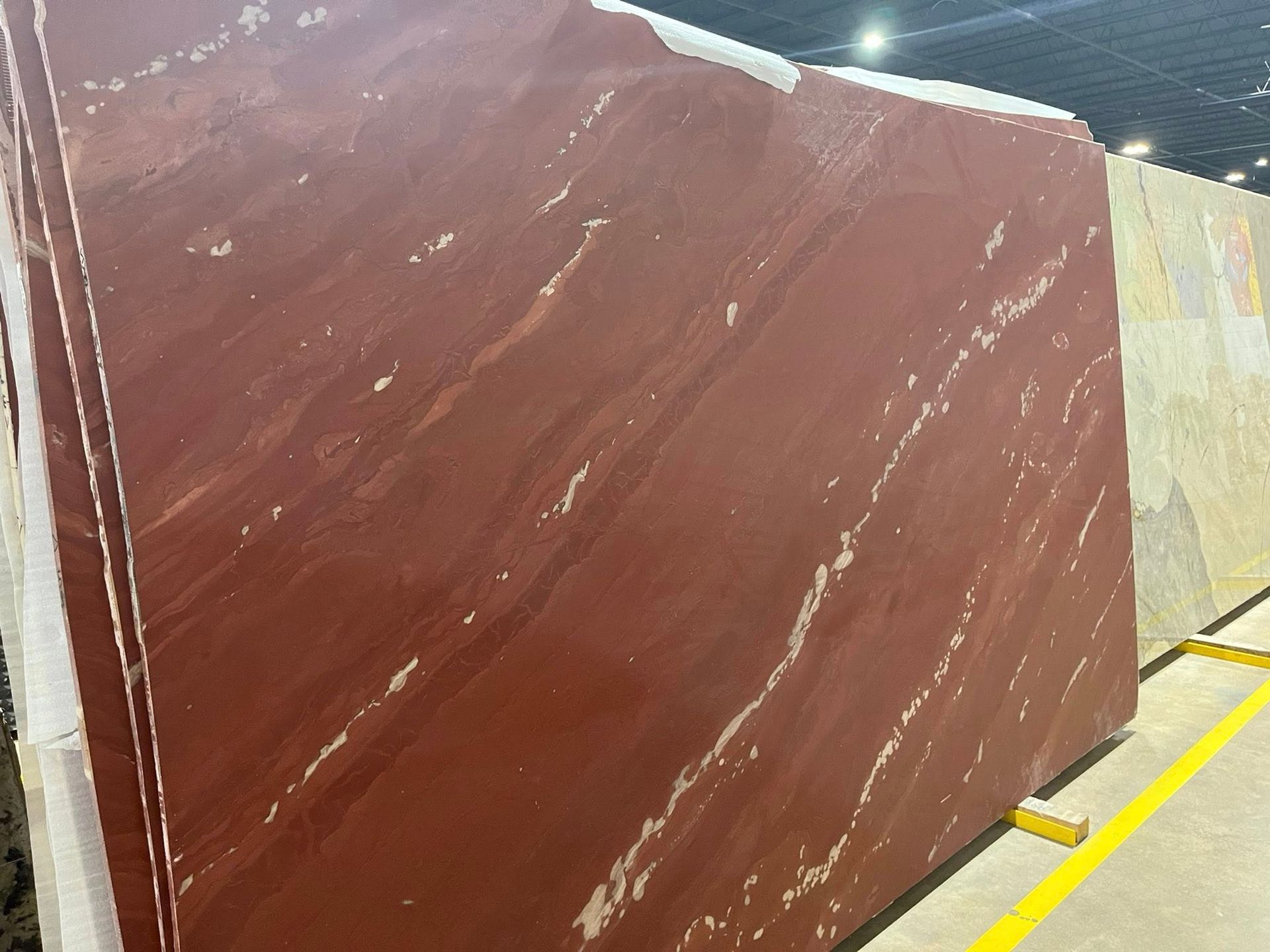 Large reddish-brown polished stone slab leaning in a showroom with other slabs behind it