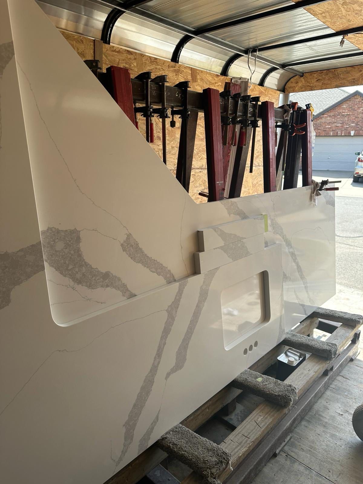 Damaged white vehicle side panel in a garage, with a large torn opening exposing interior parts.