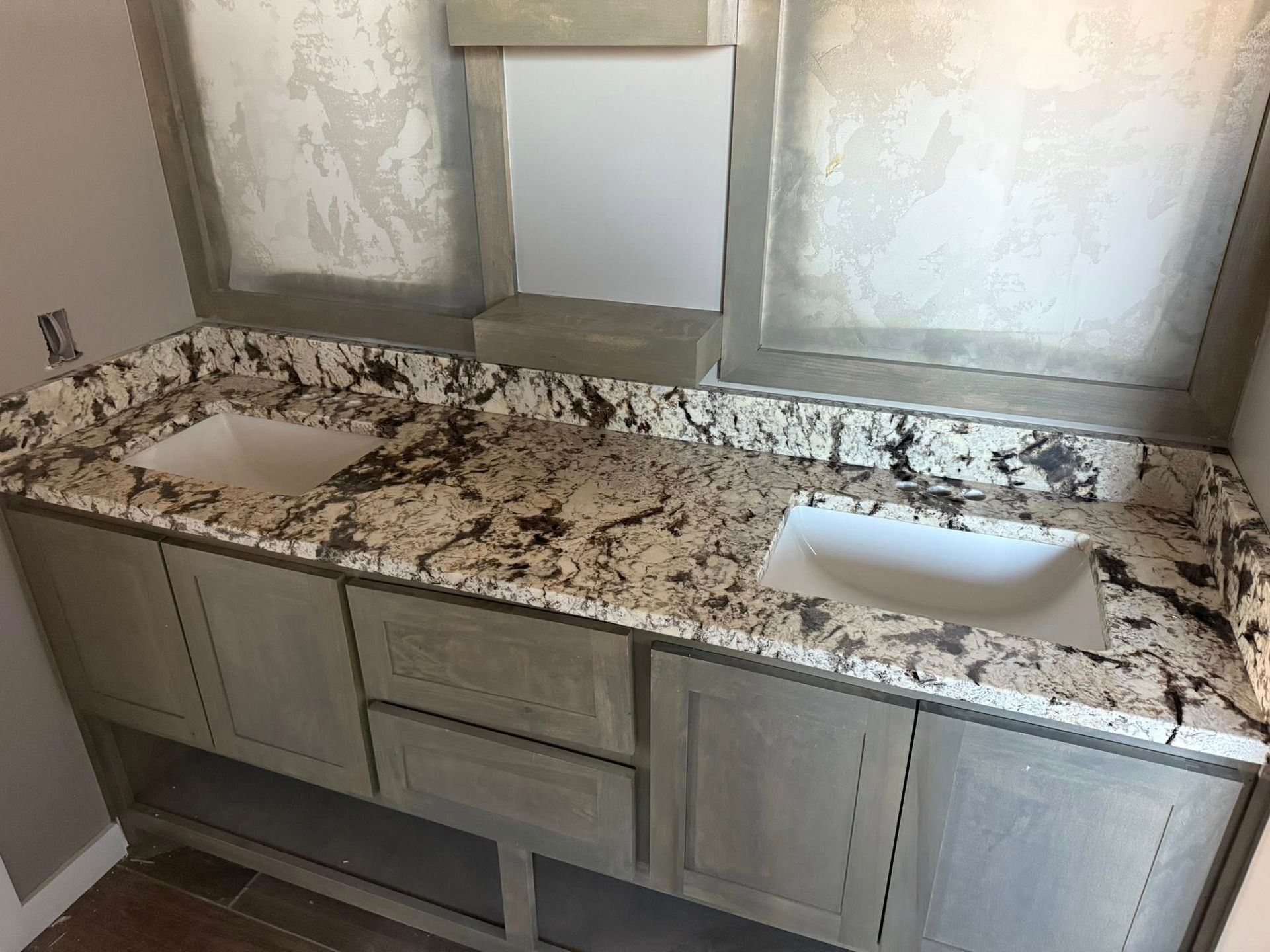 Bathroom vanity with speckled granite countertop and two sinks under a mirror.