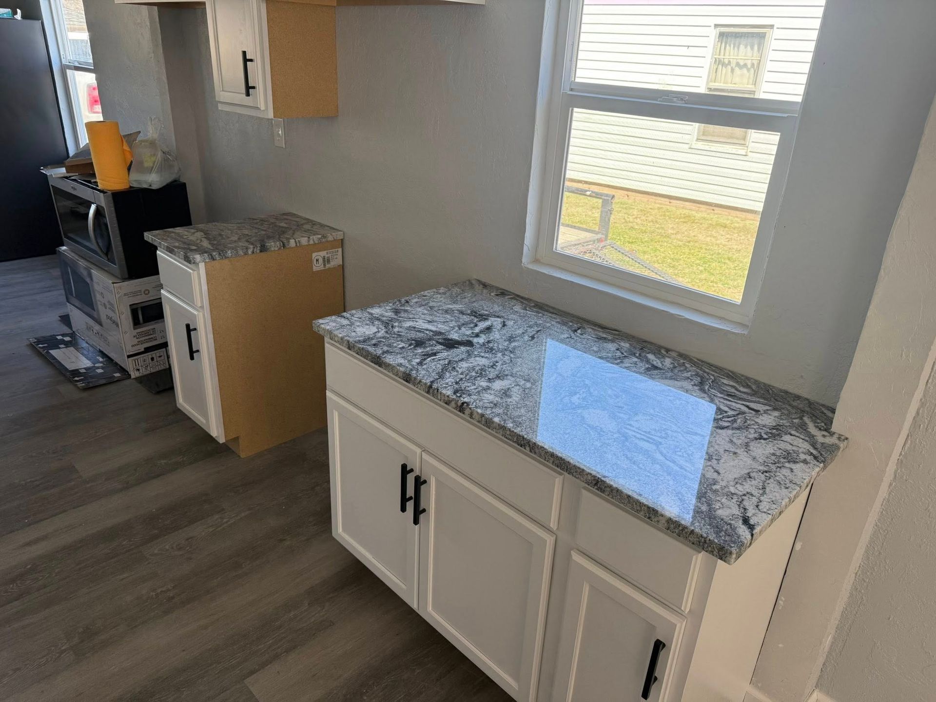 Small kitchen with white cabinets, granite countertop, window, and a stove by the wall.