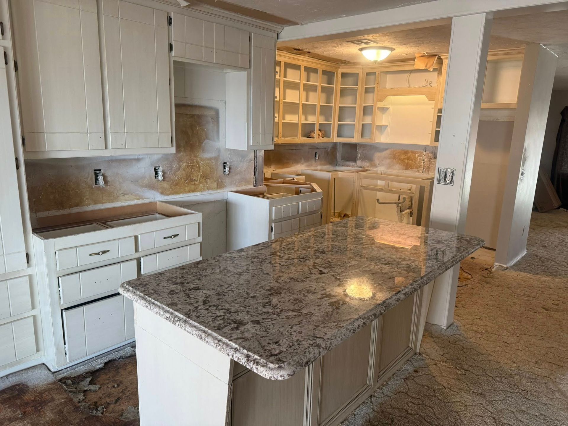 Bright white kitchen with a large granite island, built-in cabinets, and a walk-in pantry.