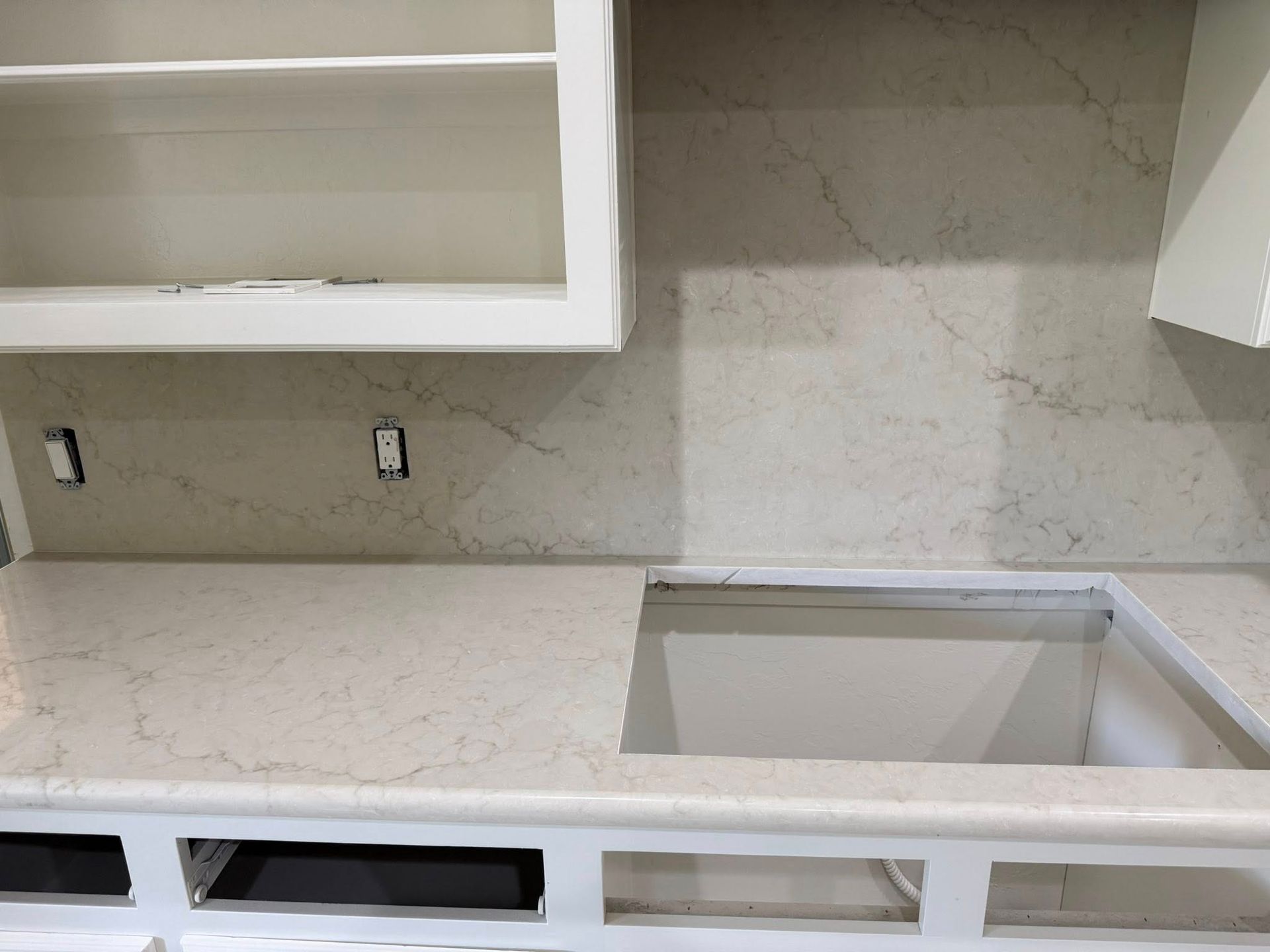 Empty kitchen countertop with light cabinets and a sink cutout