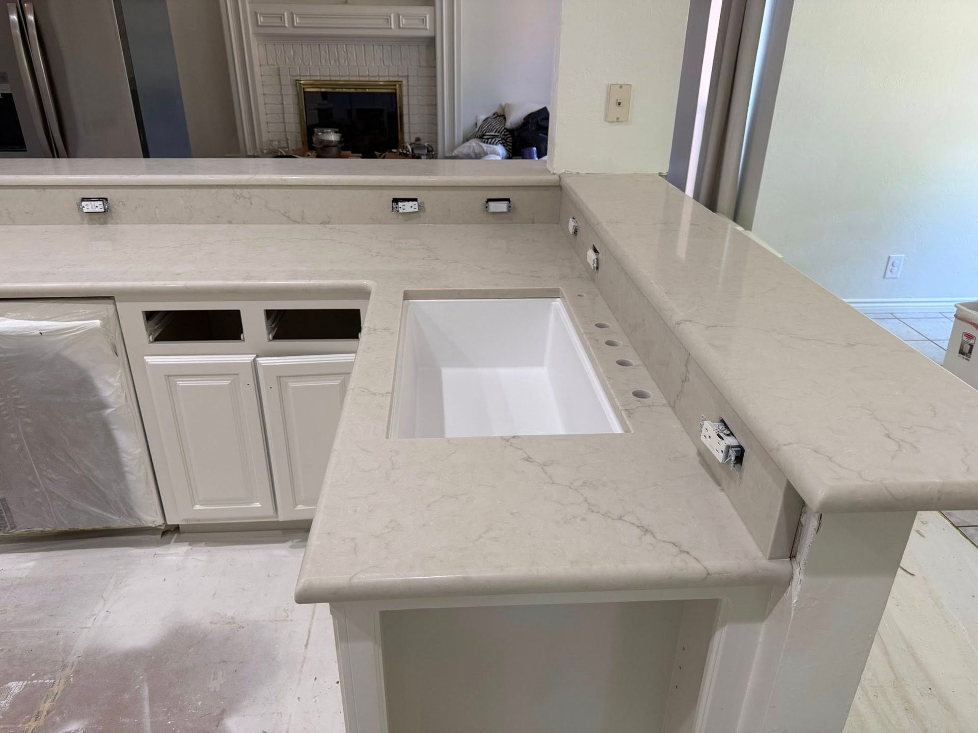 Modern bathroom vanity with light stone countertop, white cabinets, and a rectangular sink cutout.