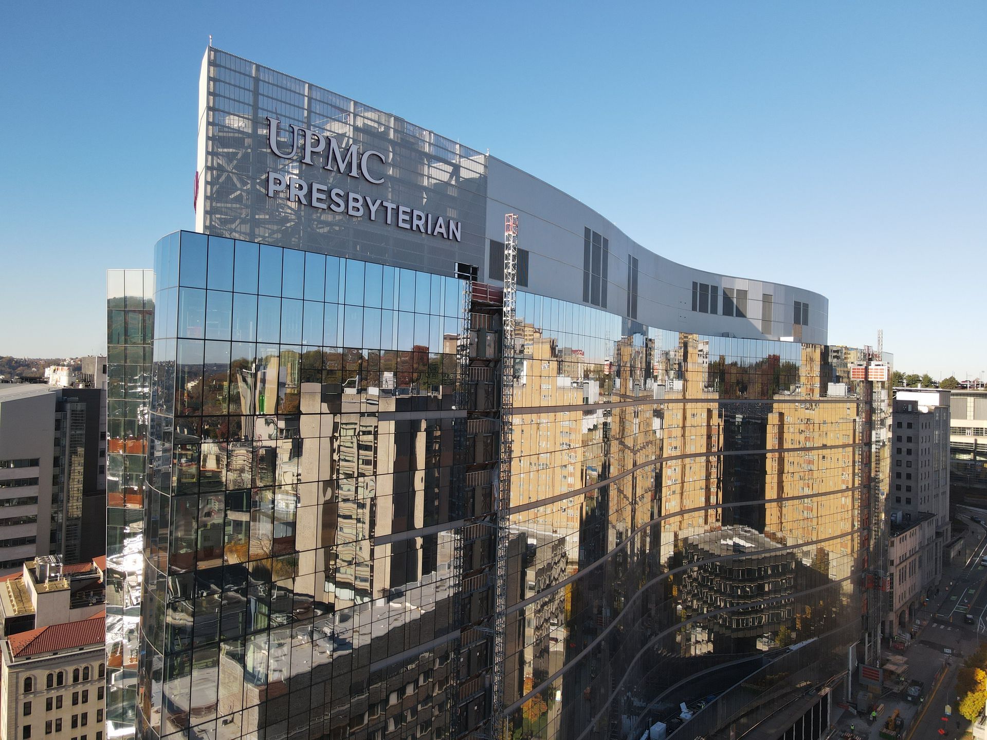UPMC Presbyterian hospital building with mirrored glass facade reflecting surroundings.
