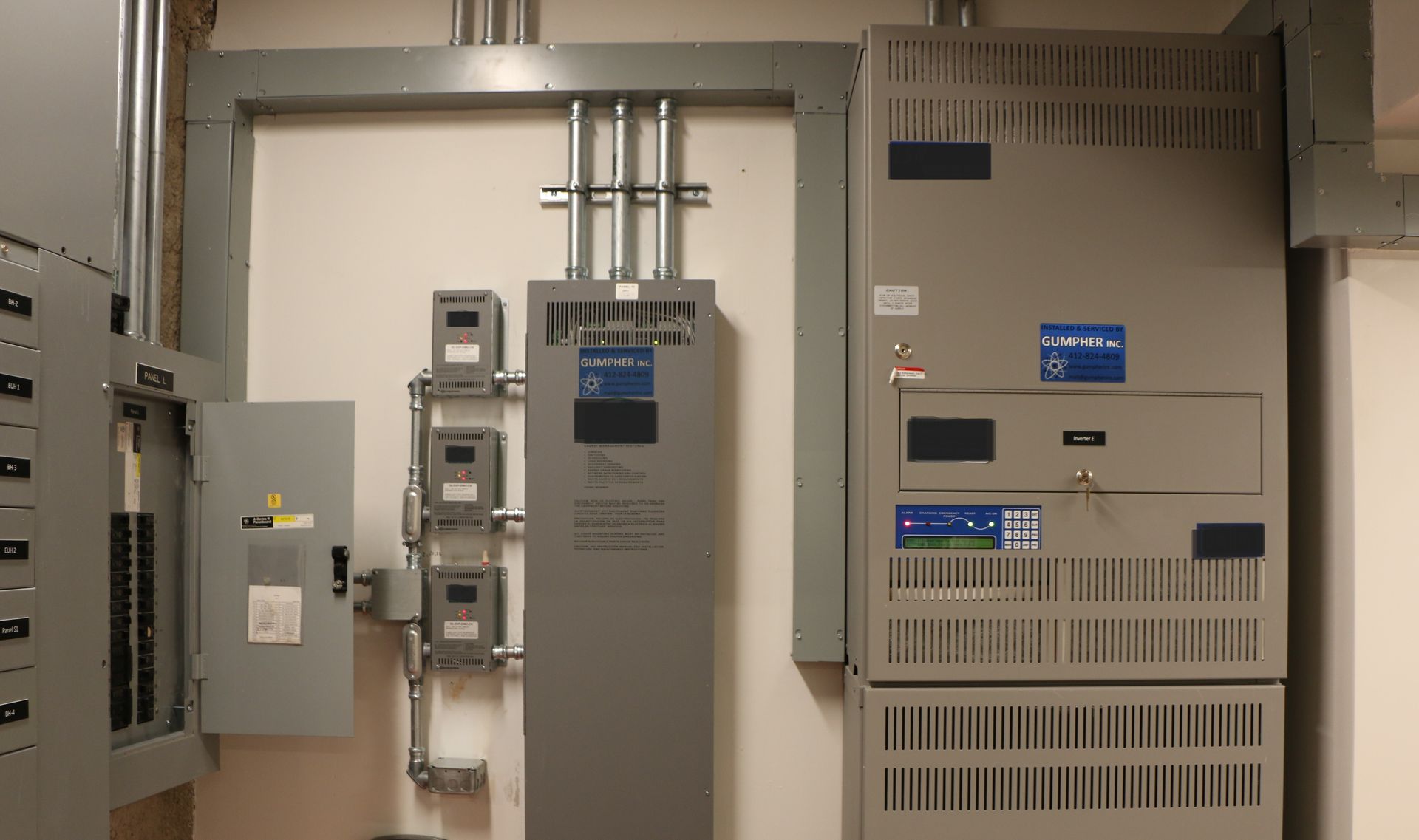 Electrical equipment room with gray metal panels, conduit, and gauges.