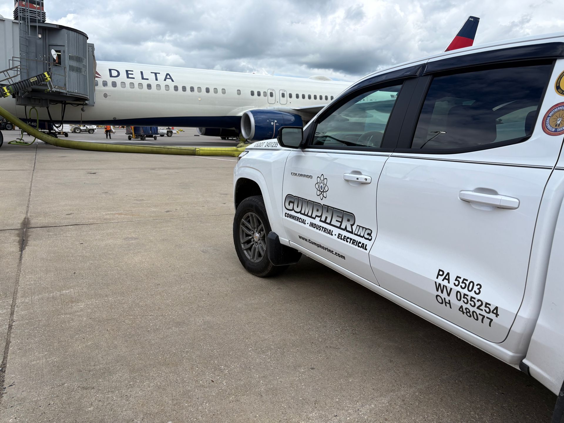 White truck parked on tarmac near a Delta plane at an airport gate.