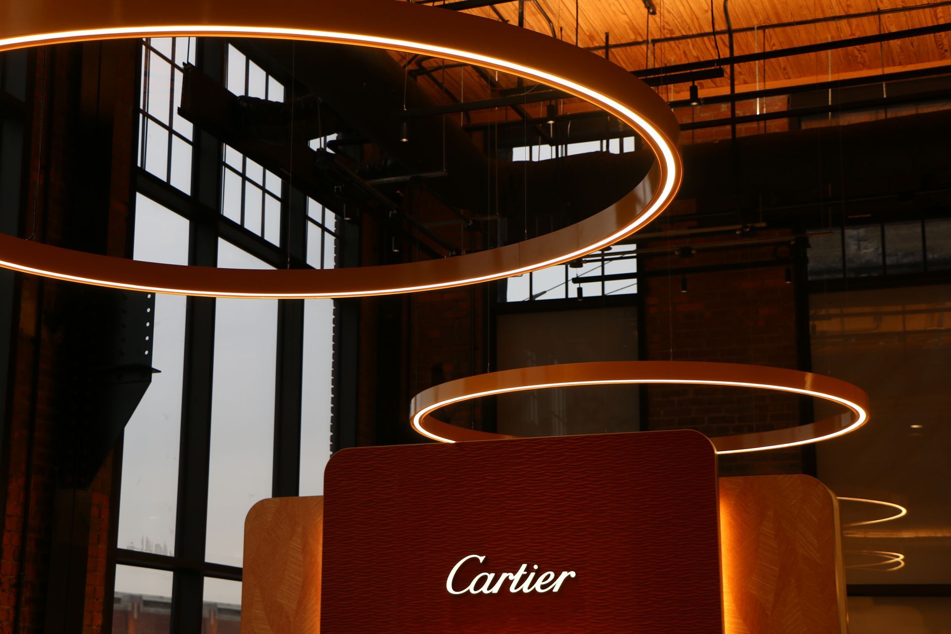 Circular lights illuminate a Cartier display in a modern building.