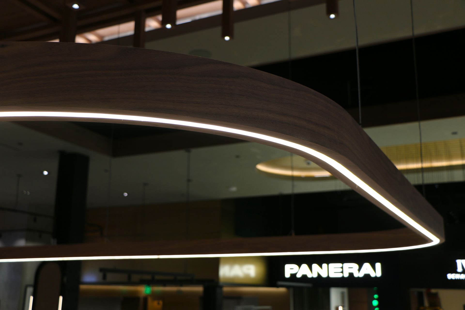 Wooden, curved ceiling light with a glowing white edge, over retail stores.