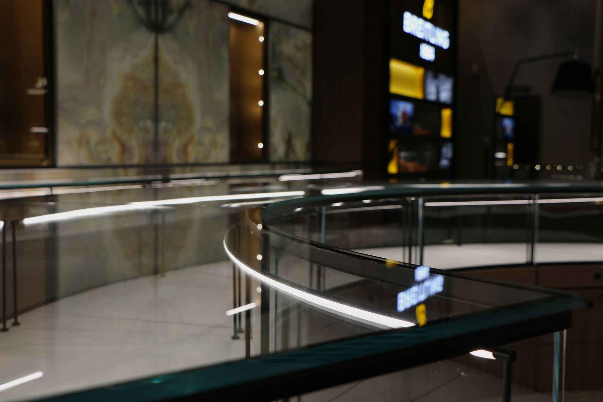 Interior of a jewelry store with curved display cases, bright lighting, and reflective surfaces.