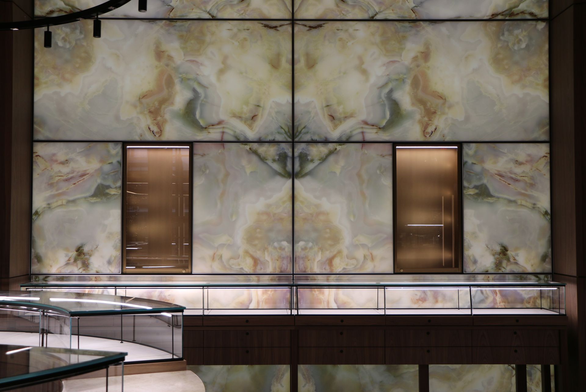Decorative wall with mirrored onyx panels and display cases.
