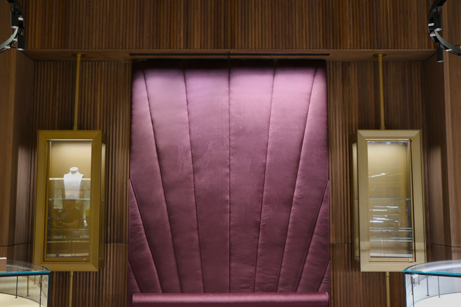 Jewelry display with a central plum-colored panel, flanked by glass display cases against a wood-paneled wall.