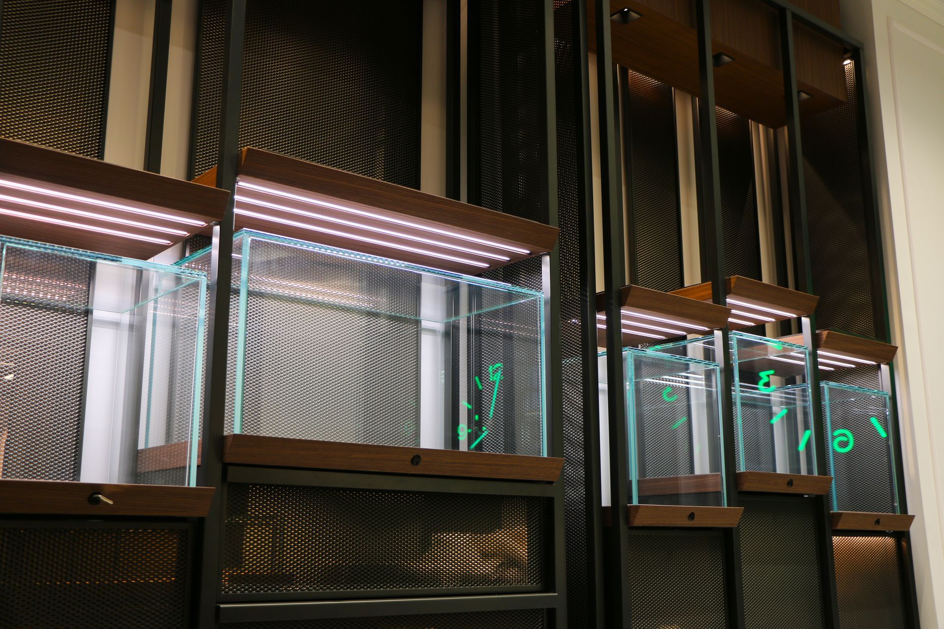Rows of lit, empty glass display cases with metal framework. Each case has a number.