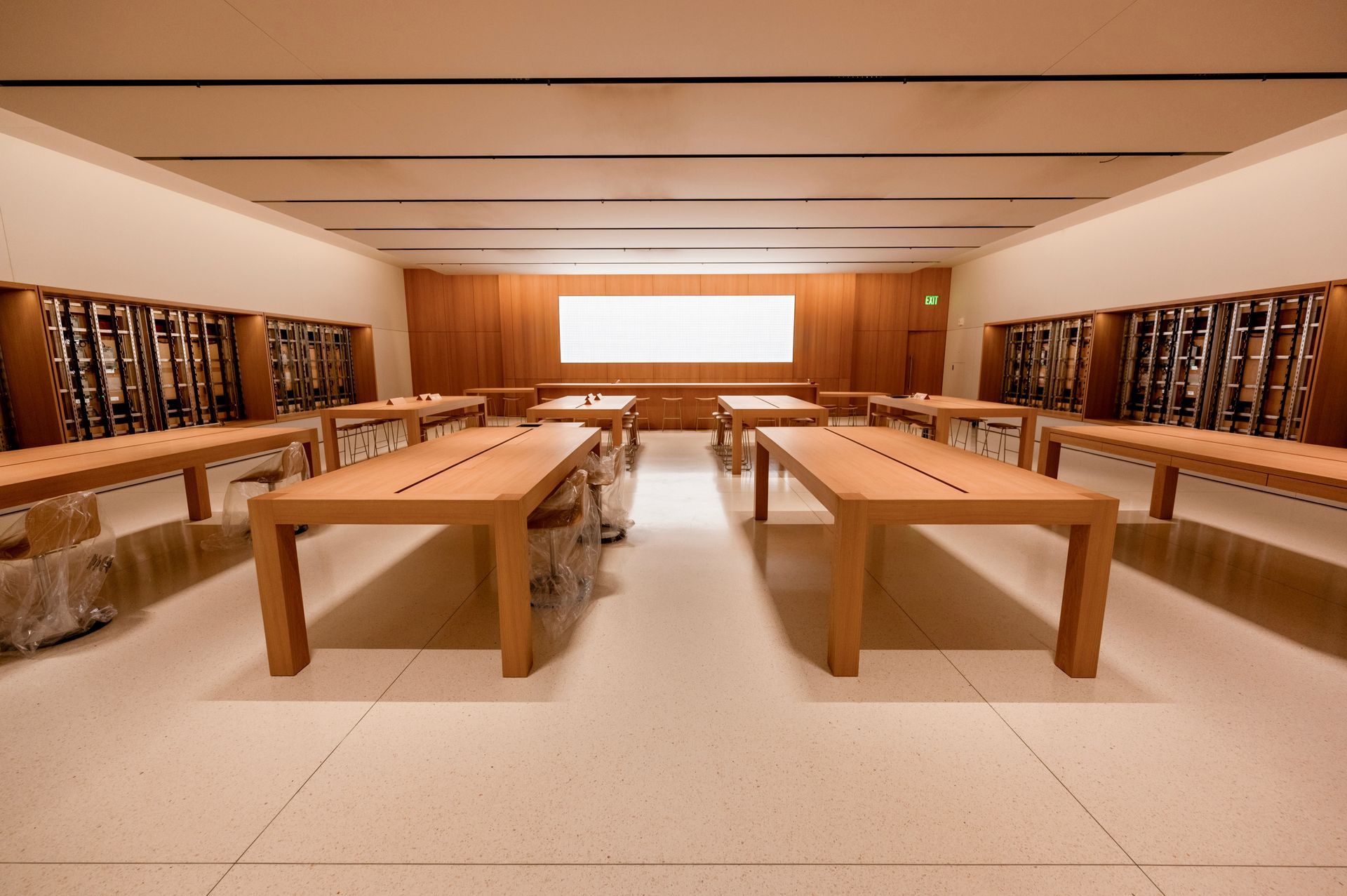 Empty Apple store interior with wooden tables and product displays.