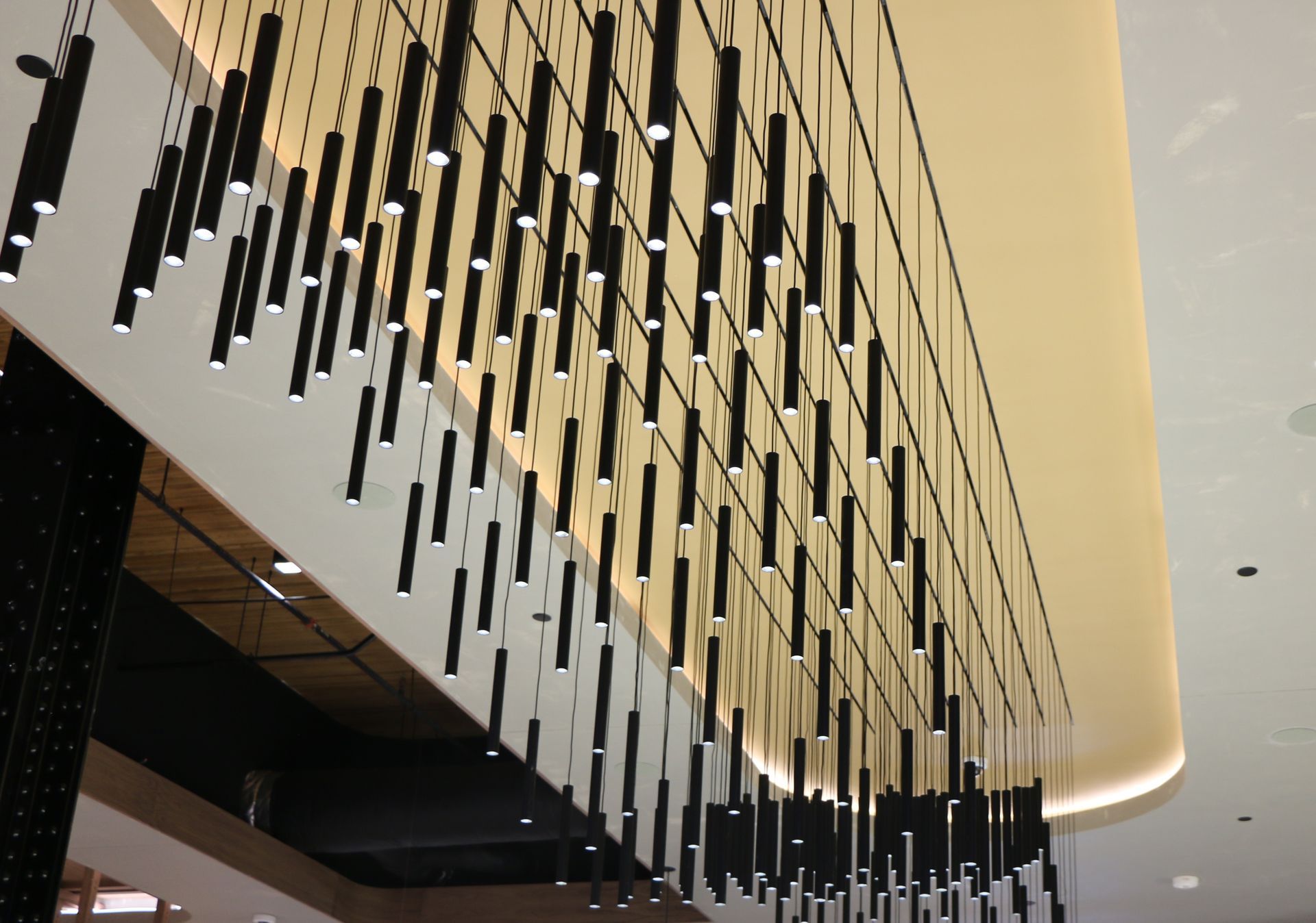 Black cylindrical lights hanging from a white ceiling, creating a decorative display.