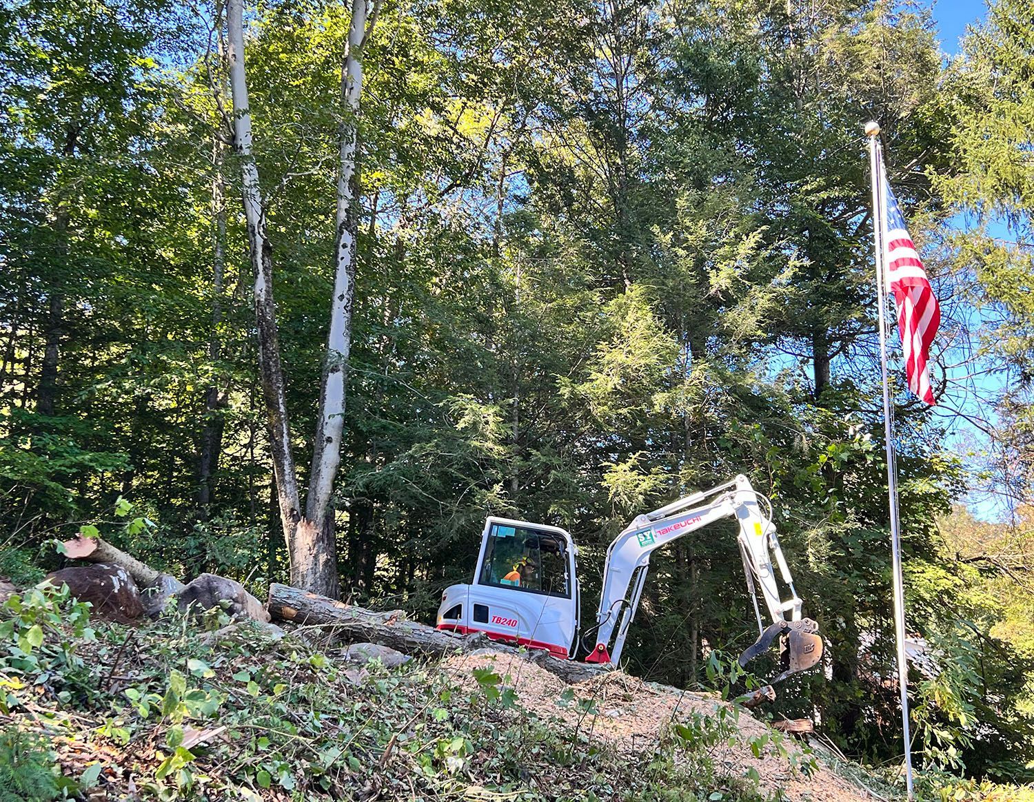 An excavator is sitting on top of a hill next to a flag