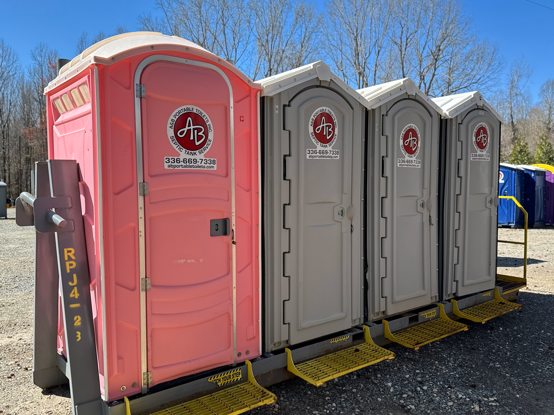 A row of portable toilets are lined up in a parking lot.