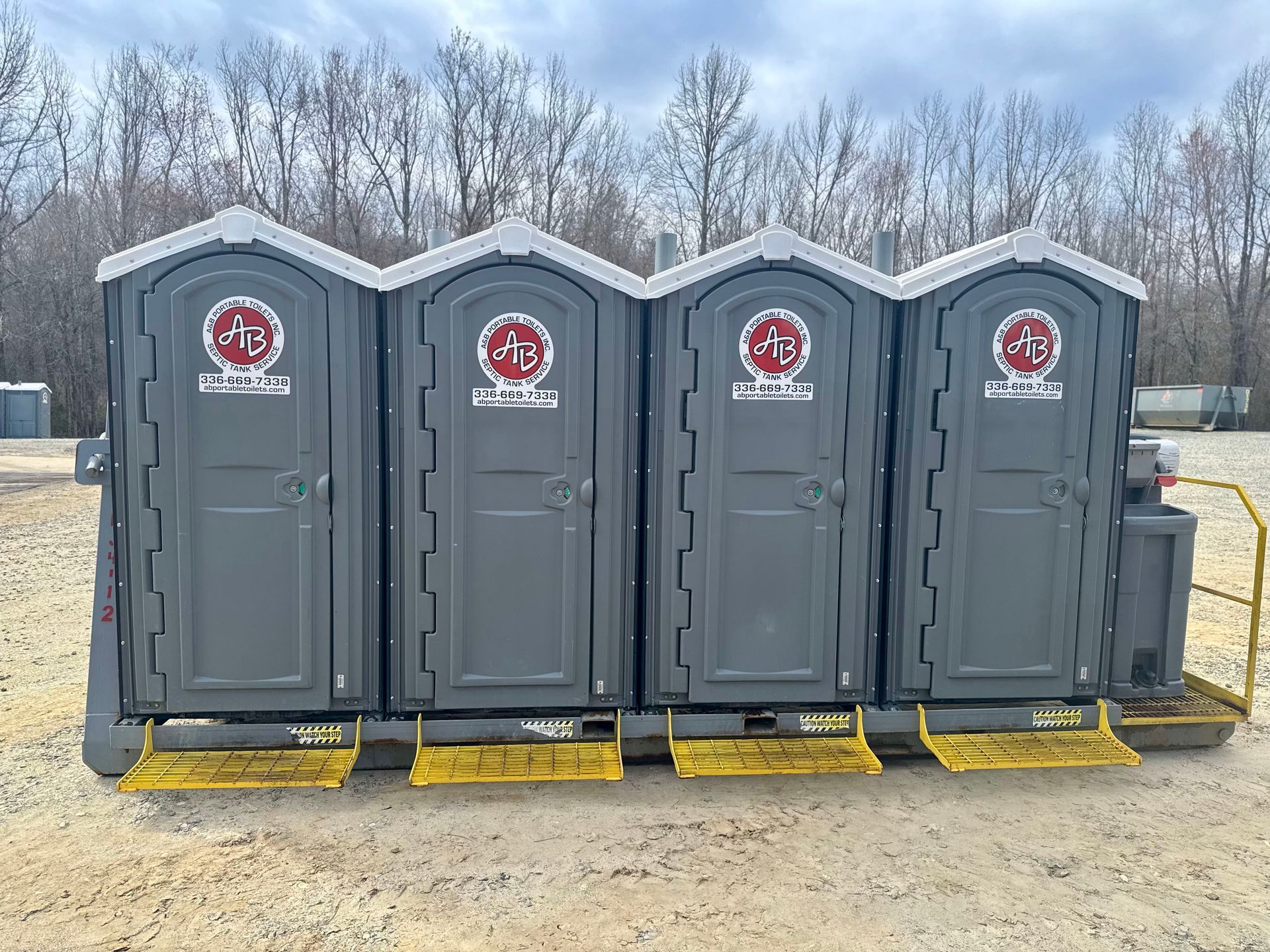 A row of portable toilets are lined up in a field.