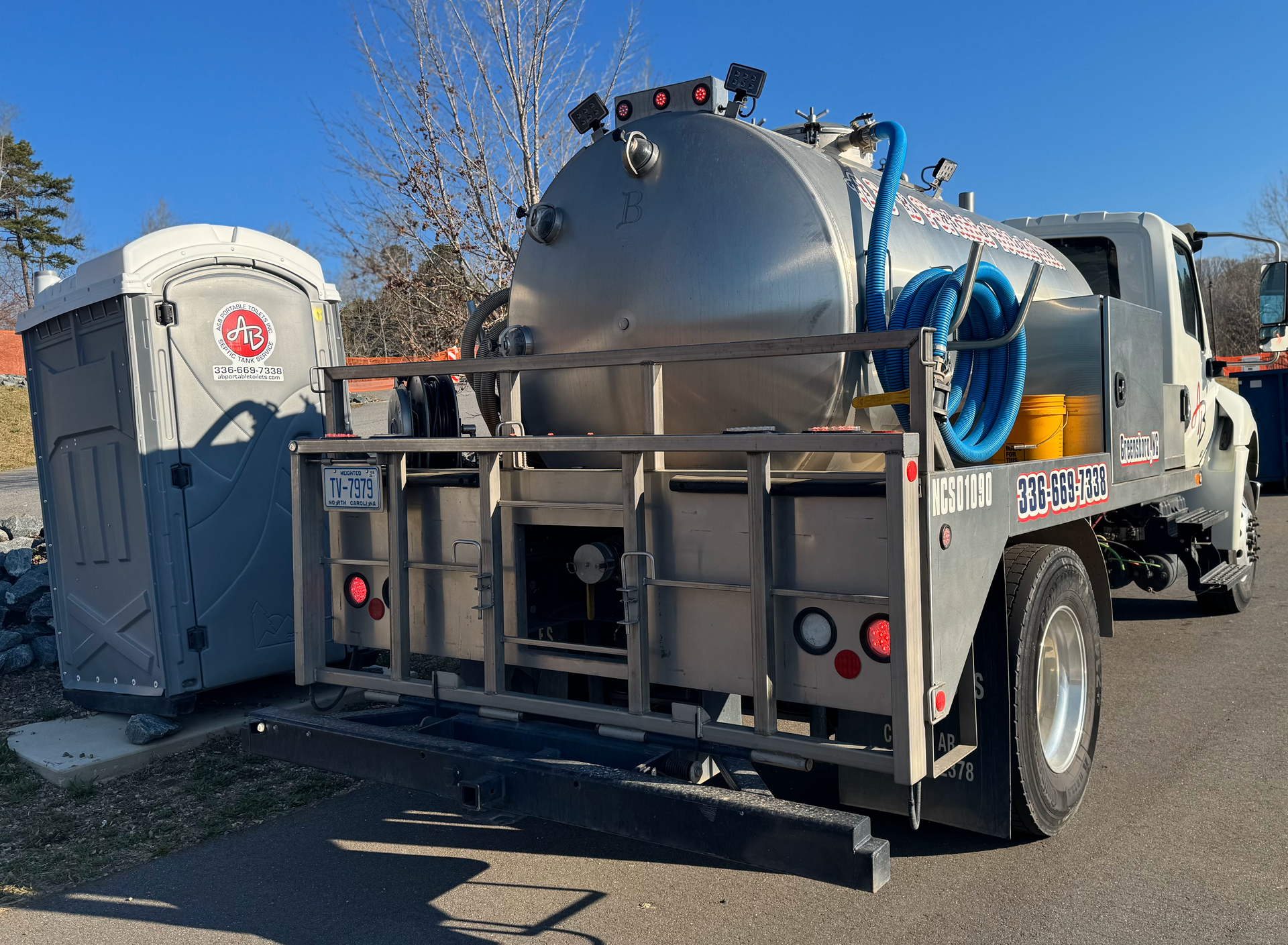 A vacuum truck is parked next to a portable toilet.