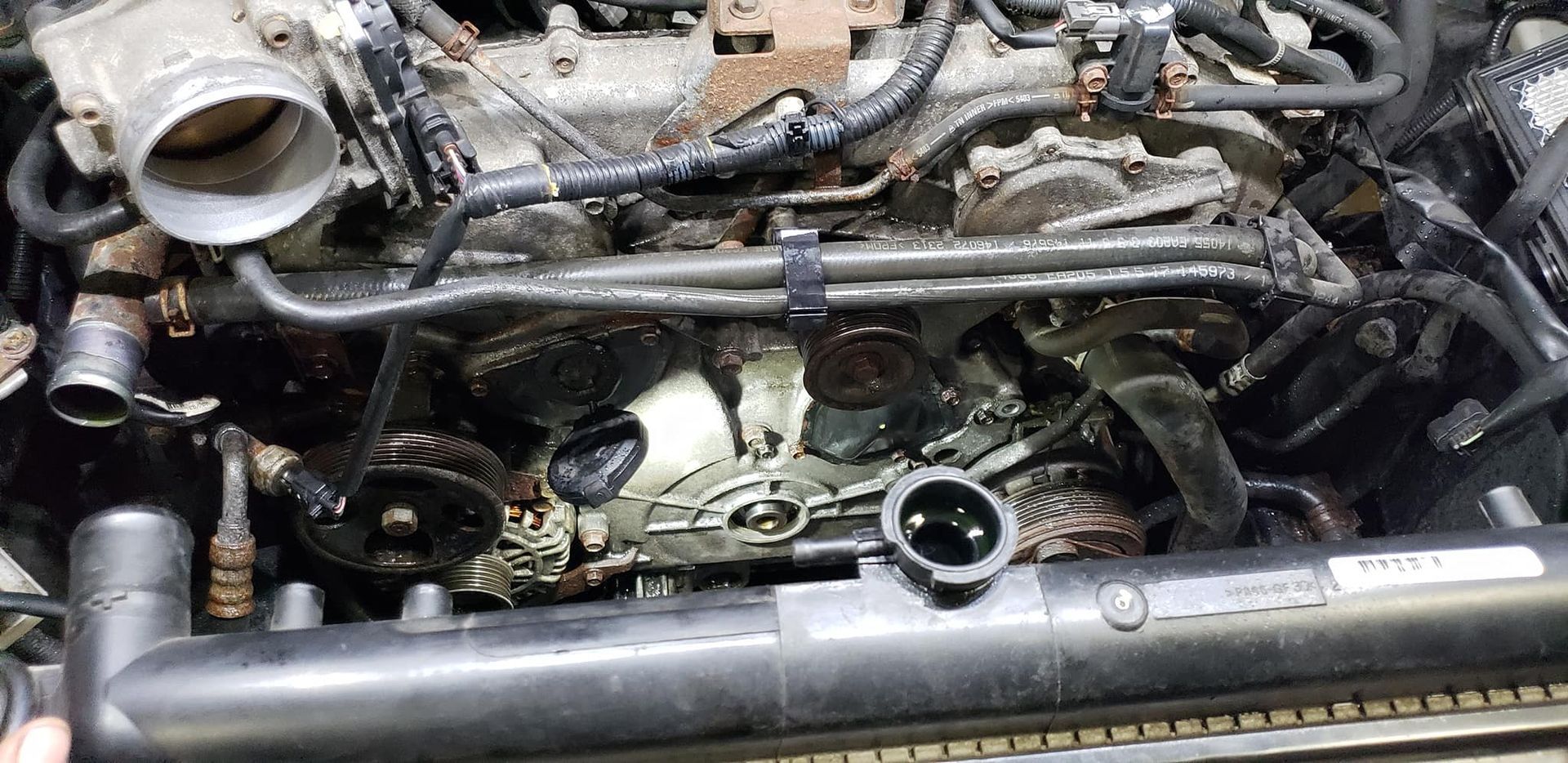 Engine bay with exposed engine components during repair.