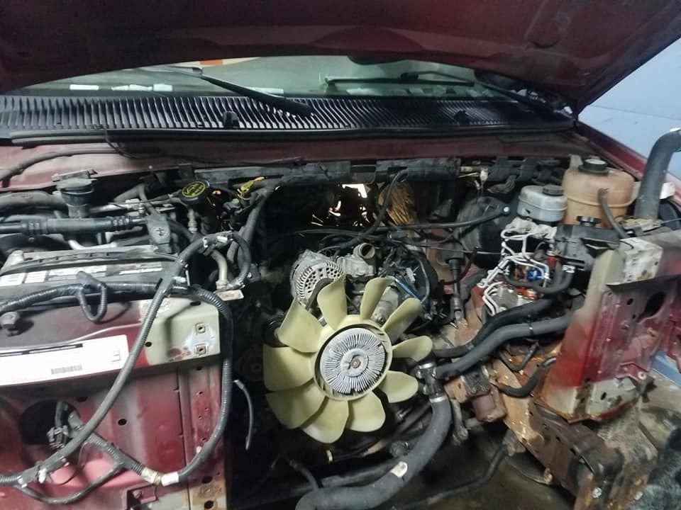Red pickup truck engine bay; fan and components exposed during repair.