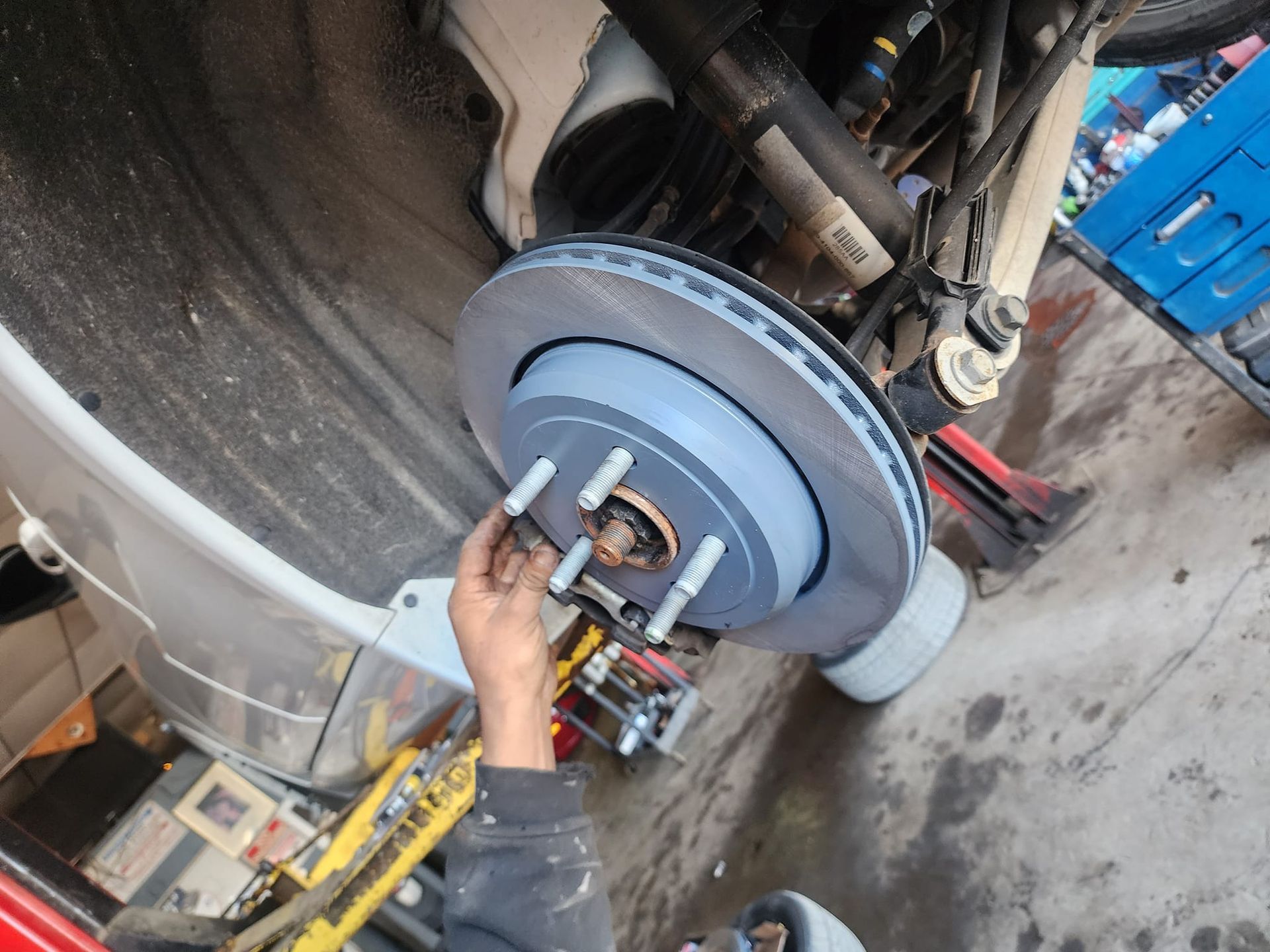 Person installing a brake rotor on a vehicle in a garage.