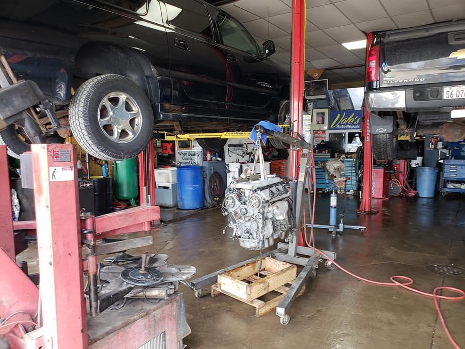 Car repair shop with a car on a lift, engine on a stand.