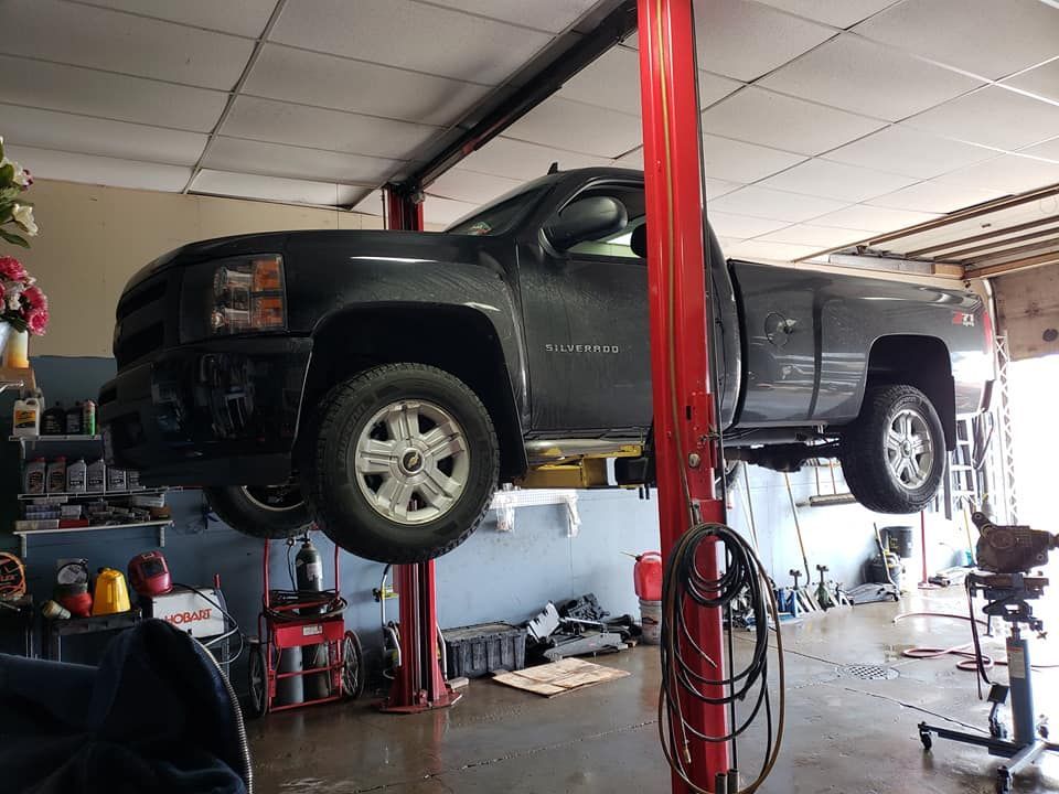 A black pickup truck on a red lift inside a garage.