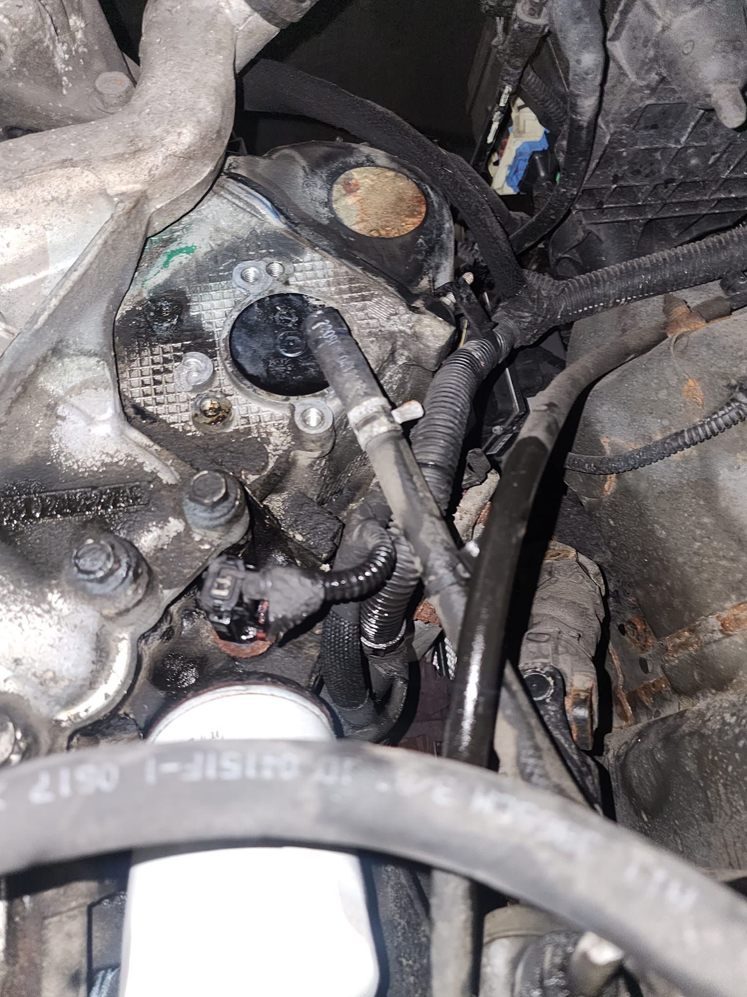 Engine compartment, oily components. Black, gray, and silver parts are visible, with a light-colored filter.