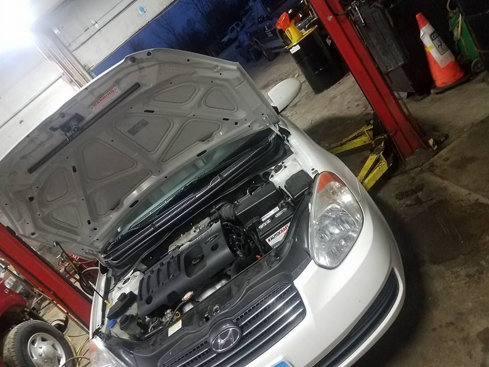 White car with open hood in a mechanic shop.