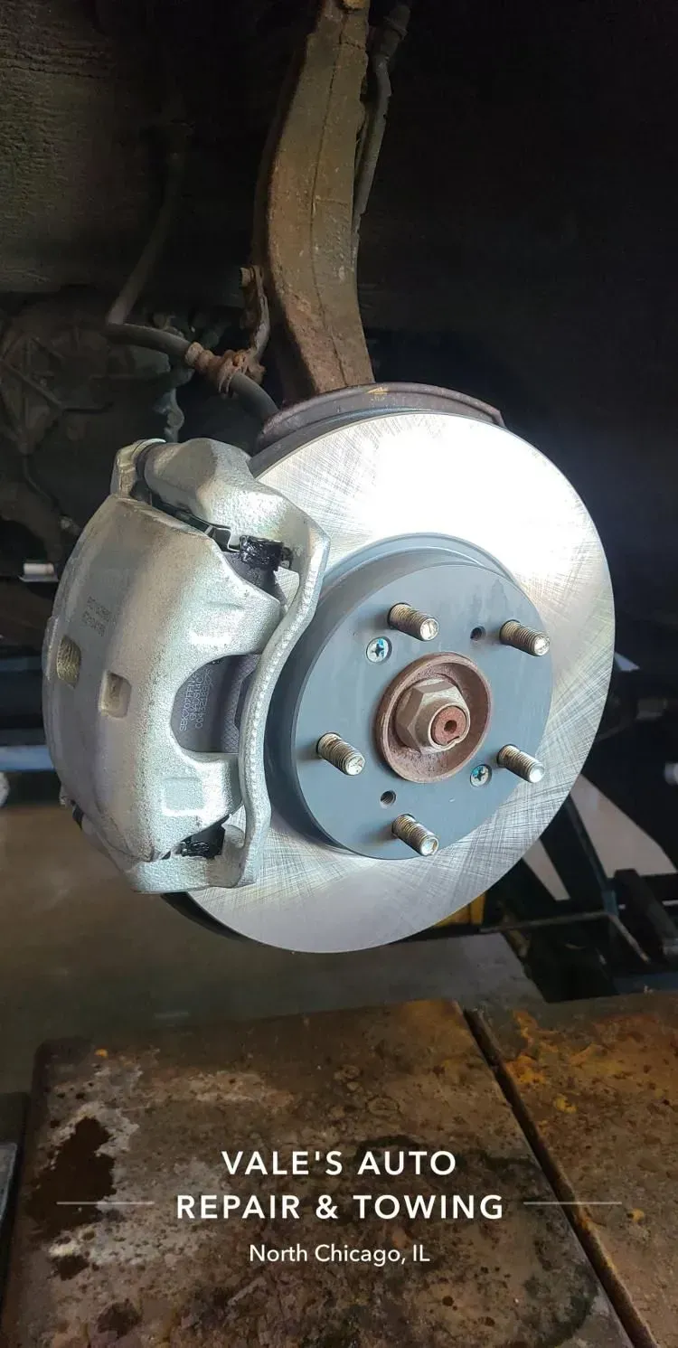 Close-up of a vehicle's brake disc and caliper, presumably at Vale's Auto Repair & Towing in North Chicago, IL.
